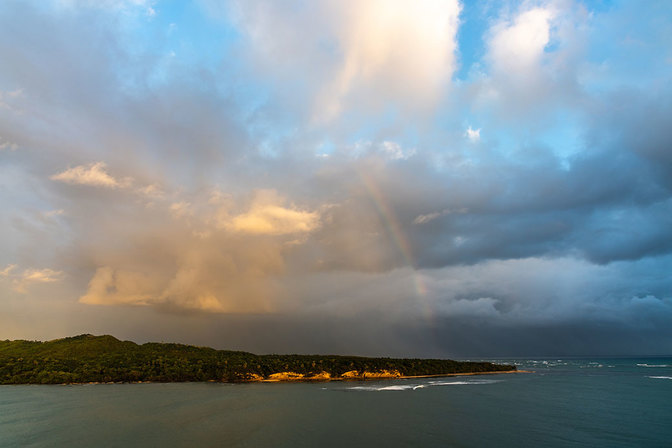 Nach einem tropischem Regenguss bringt ein Regenbogen die Amber Cove zum leuchten
